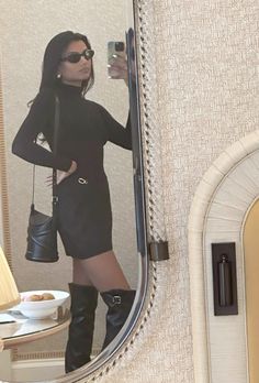 a woman taking a selfie in front of a mirror with her cell phone and purse