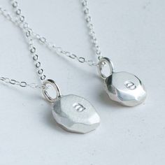 Silver initial necklace - handmade in sterling silver. Choose from polished (stamped with e in picture) or satin (stamped with a in picture) finish finish.  Its dainty and simple design is perfect for everyday wear and makes the perfect personal gift. Each pebble is handmade with a faceted edge to really catch the light. As each is made from scratch the exact sape and size will differ ever so slightly from the picture.  Dimensions: - each pebble is approximately 8-10mm wide and 3mm thick - Initi Simple Silver Initial Pendant Name Necklace, Minimalist Sterling Silver Initial Pendant Name Necklace, Sterling Silver Minimalist Initial Pendant Charm Necklace, Simple Silver Initial Pendant Necklace, Simple Sterling Silver Initial Pendant Necklace, Minimalist Initials Sterling Silver Necklace, Simple Sterling Silver Initial Pendant Charm Necklace, Sterling Silver Initial Pendant For Bridesmaid, Dainty Sterling Silver Initial Pendant Name Necklace