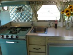 a kitchen with sunflowers in vases on the window sill and blue cabinets