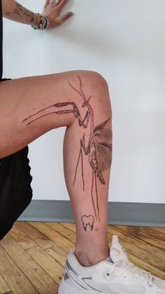 a man with a tattoo on his leg is sitting in front of a white wall