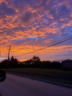 the sun is setting behind power lines and telephone poles on the side of the road