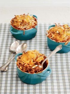 three blue casserole dishes on a checkered tablecloth with silver spoons