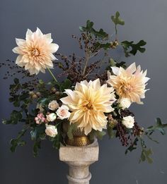 a vase filled with lots of flowers on top of a table next to a wall