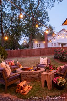 an outdoor fire pit surrounded by chairs and lights