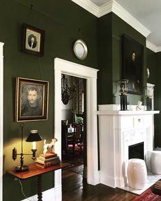 a living room with green walls and pictures on the fireplace mantels in it