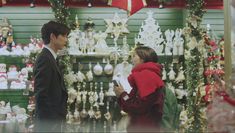 a man and woman standing next to each other in front of a christmas decoration display