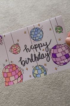 a hand holding up a birthday card with colorful balloons and the words happy birthday written on it