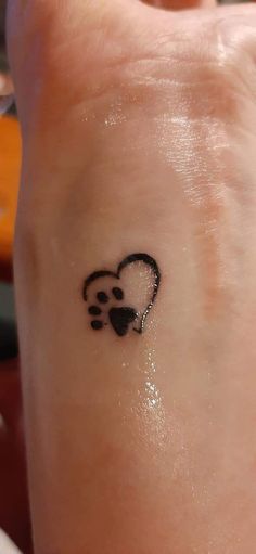 a small heart tattoo on the wrist with a paw print in it's center