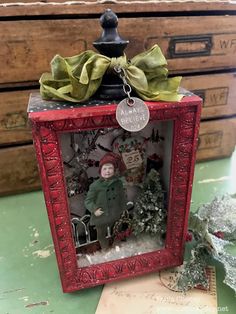 a small red box with a christmas decoration inside