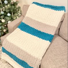 a blue and white crocheted blanket sitting on top of a couch next to a christmas tree