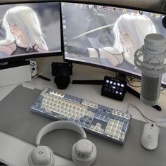 two computer monitors sitting on top of a desk next to headphones and a microphone