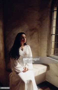 a woman sitting on a bench in front of a window with sunlight streaming through it