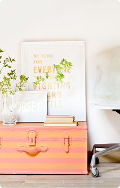 a pink suitcase sitting on top of a wooden table next to a plant and pictures