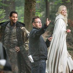 the actors are walking through the woods in medieval costumes, and one is pointing at something