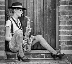 black and white photograph of a woman sitting on the steps with a saxophone in her hand