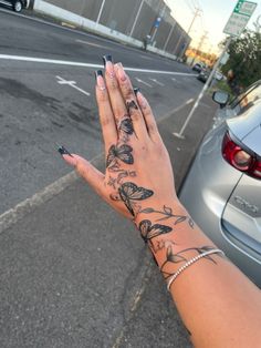 a woman's hand with tattoos on it is next to a car and street