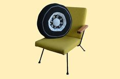 a green chair with a black and white fan on it's backrest, sitting in front of a yellow background