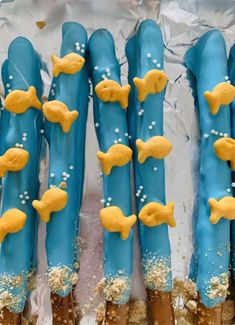 some blue and yellow decorated sticks with gold fish on them in the shape of toothpicks