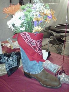 a pair of boots with flowers in them sitting on a table next to other items