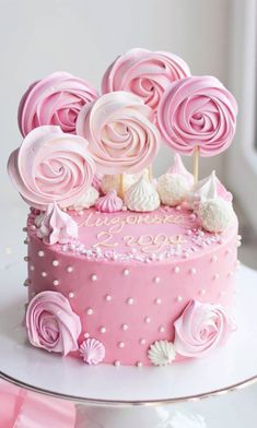 a pink birthday cake with white frosting roses on top