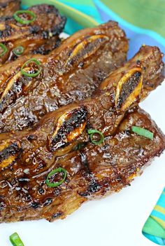 grilled meat on a white plate with green onions