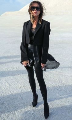 a woman standing in the snow wearing all black