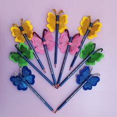 six butterfly shaped pencils are arranged in the shape of flowers and butterflies with glitter on them