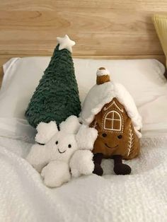 two stuffed animals sitting on top of a bed next to a christmas tree and a gingerbread house