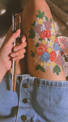 a woman with flowers painted on her leg holding a wrench