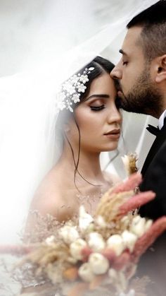 a bride and groom are kissing under the veil