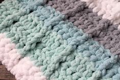 a crocheted blanket is laying on a wooden surface