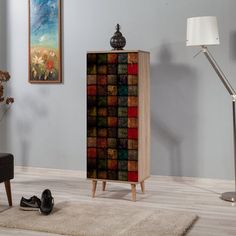 a room with a chair, rug and painting on the wall next to a cabinet