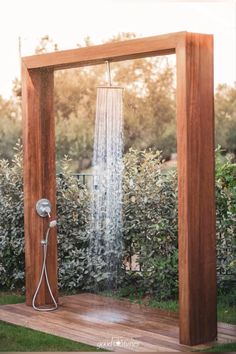 an outdoor shower in the middle of a wooden frame with water coming out of it