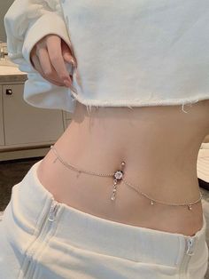 a woman wearing a white shirt with a silver chain around her waist and the bottom part of her stomach