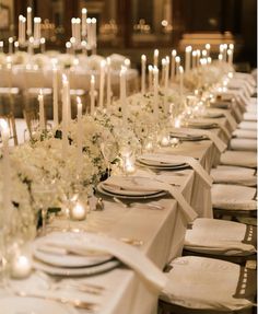 a long table is set with white flowers and candles