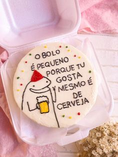 a decorated cake in a plastic container with writing on the side and an image of a person holding a beer