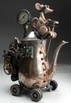 a metal teapot with a clock on the top and wheels attached to it's sides