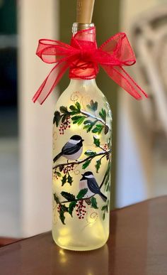 a glass bottle decorated with birds and holly