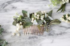 the bridal comb is adorned with flowers and greenery on a marble table top