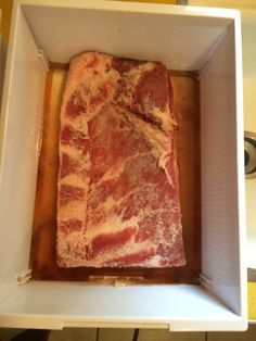 meat in a square white container sitting on top of a stove