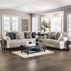 a living room with two couches and a coffee table in front of the windows