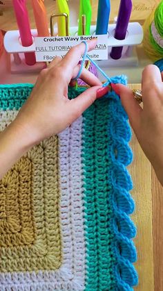 someone is crocheting together with yarn on the table next to some scissors and knitting needles