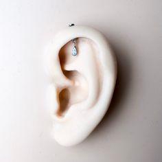 an ear with a single diamond hanging from it's side on a white surface