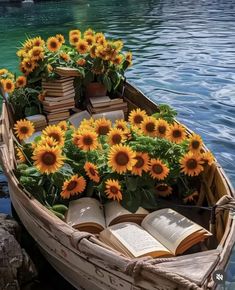 a row boat filled with books and sunflowers floating on top of the water