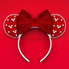 a red minnie mouse ears headband with pearls on it's side and a bow at the top