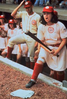 a woman holding a baseball bat in front of a group of people wearing red and white uniforms