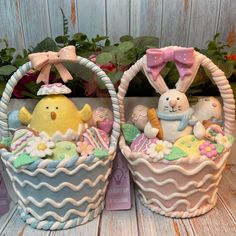 two baskets with easter decorations on them sitting next to each other in front of flowers