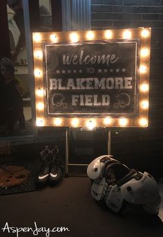 a sign that is lit up with lights and some football helmets in front of it