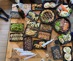 a wooden table topped with lots of trays of food