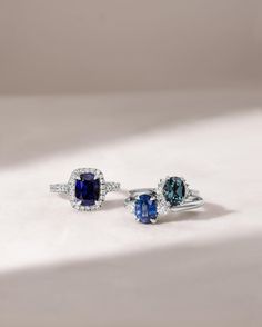 two blue and white diamond rings sitting on top of a white surface with shadows coming in from the background